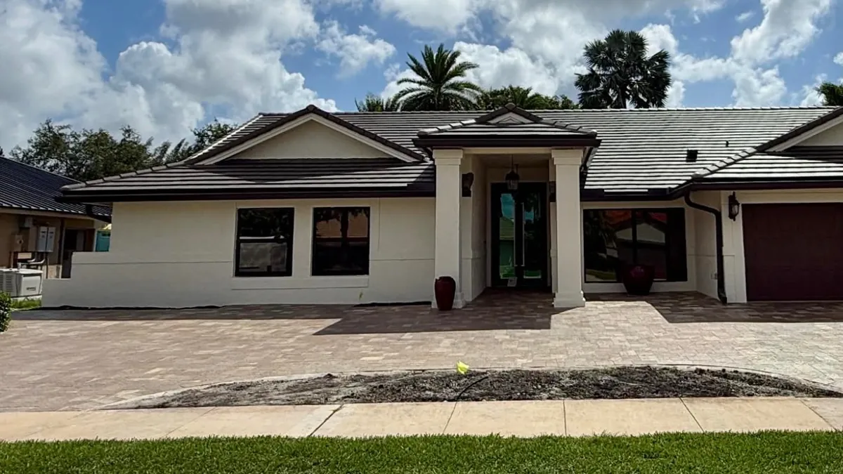 The same front elevation before any planting, with bare beds and an empty driveway apron