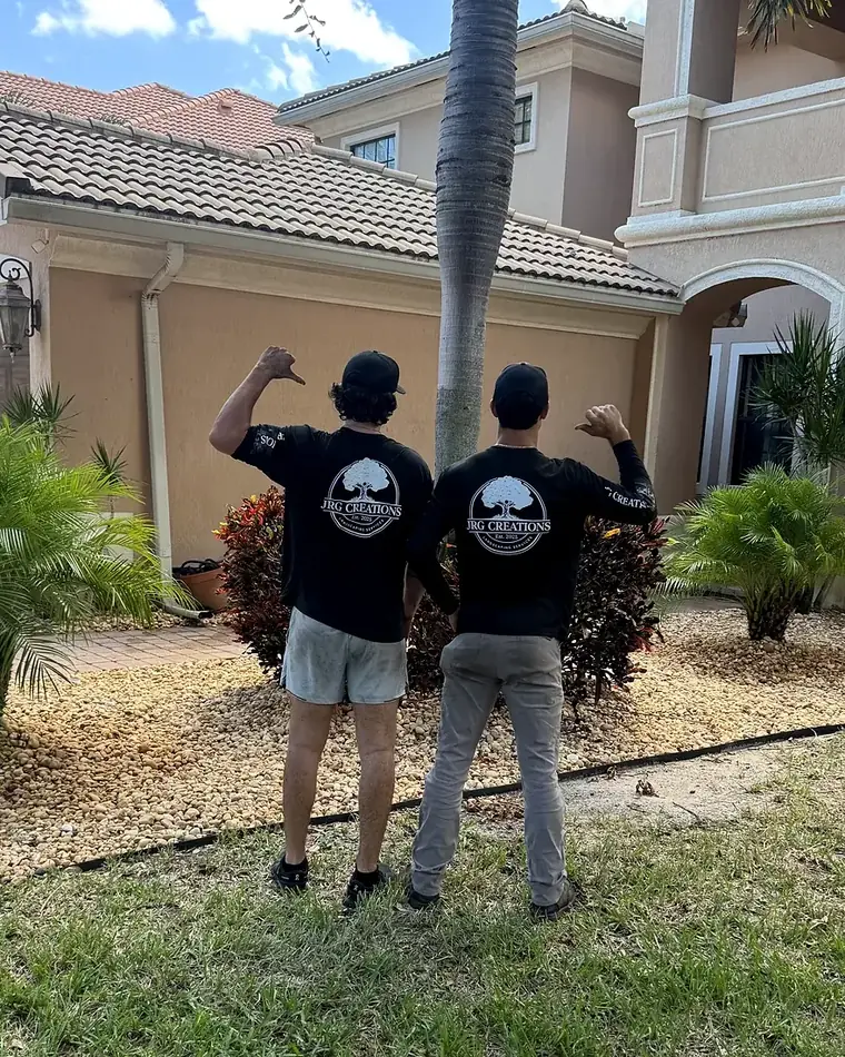 Two JRG Creations crew members in company shirts in front of a finished front yard